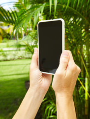 Woman with a smartphone in tropical garden.