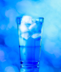 Glass of water on blue background. water with ice in glass