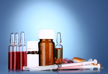 medical ampules, bottles, pills and syringes on blue background