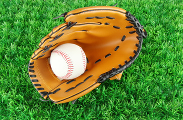 Baseball glove and ball on grass background