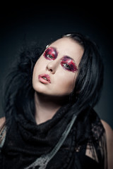 portrait of young brunette woman with fashion makeup on dark