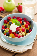 Obstsalat in blauer Schüssel auf Holzuntergrund