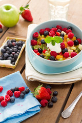 Obstsalat in blauer Schüssel auf Holzuntergrund