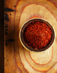 red hot chillies pepper  flakes in bowl on wooden board  backgro