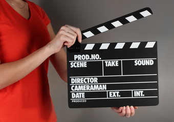 Movie production clapper board in hands on grey background