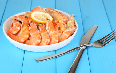 Shrimps with lemon on plate on wooden table close-up