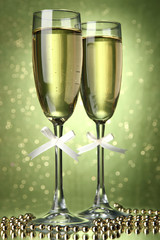 Two glasses of champagne on bright background with lights