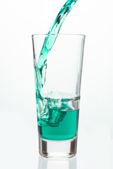 Glass being filled with green liquid