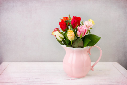 Roses flowers in pink jug on wooden vintage table