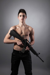 Fototapeta premium Handsome bare-chested soldier is holding a rifle