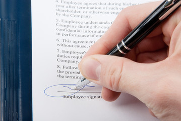 Hand with a pen signing an agreement