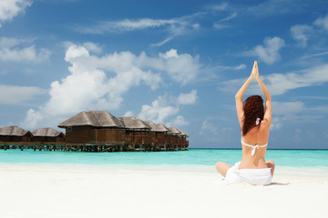 woman doing yoga exercises on the beach