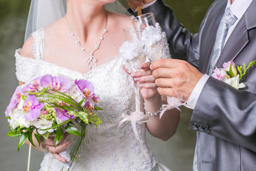 Wedding glasses in hands of groom and bride