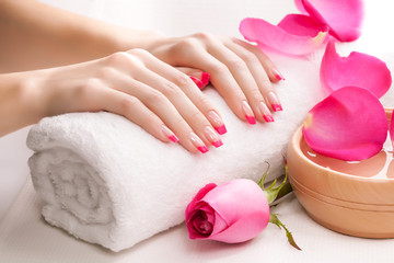 Obraz na płótnie Canvas beautiful pink manicure with fragrant rose petals and towel. Spa