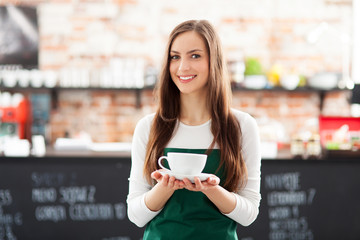 Waitress holding cup of coffee in cafe