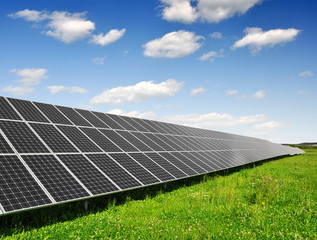 Solar energy panels against blue sky with clouds