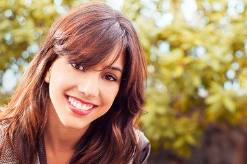 Naklejka premium Portrait of a brunette girl outdoors on a green background