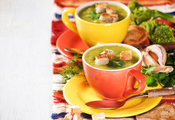 Two cheerful cup with green broccoli soup and dry toast