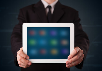 Businessman holding a white modern tablet with blurry apps