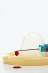 Rolled up condom and syringe dripping blood