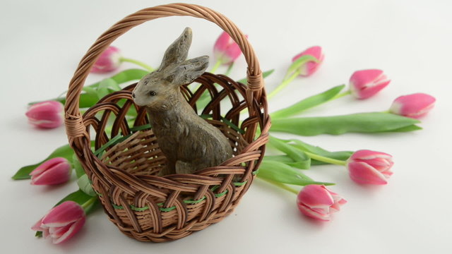 Putting Easter eggs in basket with bunny and tulips