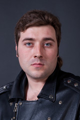 young man in a leather jacket on a gray background