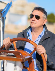 Mature Man Holding Steering Wheel Of Sailboat