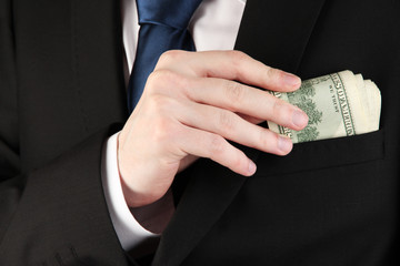 Business man hiding money in pocket close-up