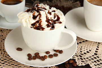 Cup of whipped cream coffee on wooden table close up