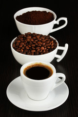 Different types of coffee in three cups on wooden table