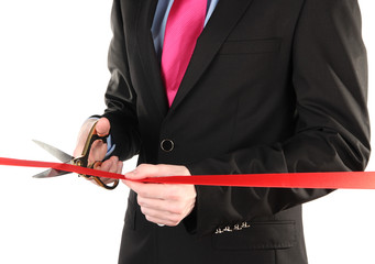 Man's hand cutting red ribbon with pair of scissors for