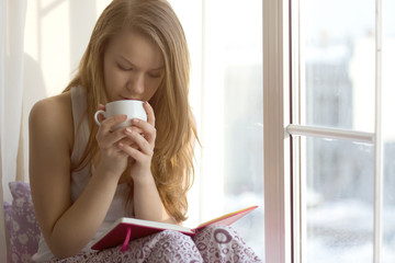 Girl near the window drinking tea