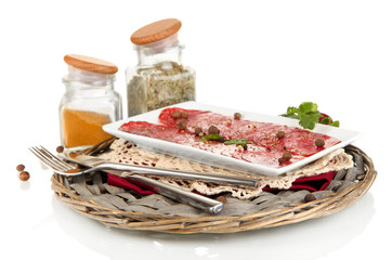 Tasty salami on plate on  wicker cradle isolated on white