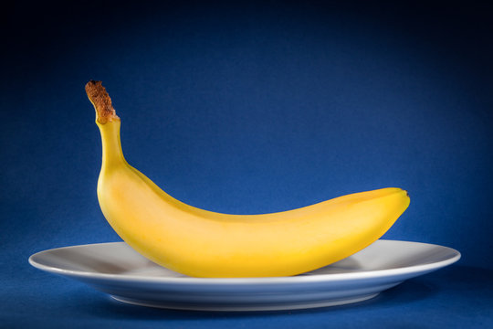 yellow banana on a white dish over a blue background