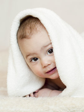 Happy smiling baby under a white towel