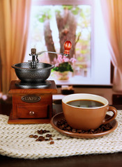 cup of coffee with scarf and coffee mill on table in room