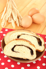 Loaf with poppy seeds on color plate, on wooden background