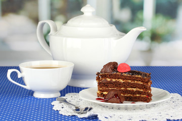 Teapot, cup of tea and delicious cake on window background