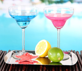 Glasses of cocktails on table near pool