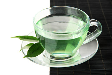 Transparent cup of green tea on bamboo mat, isolated on white