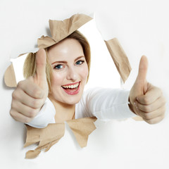 Pretty woman with thumbs up smiling through paper hole