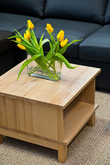 Vase with yellow tulips on wooden coffee table
