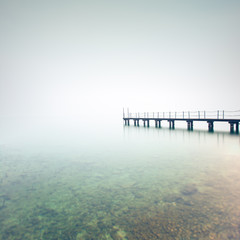 Pier or jetty silhouette in a foggy lake. Garda lake, Italy