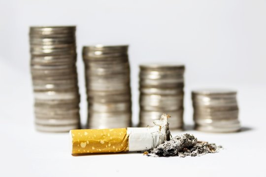 Single cigarette butt with ash and coin stack