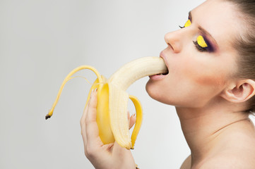 photo young sexy woman eating peeled banana, on light backgrownd