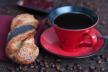 Bun with seeds next to red coffee cup