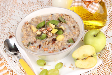 Useful oatmeal in bowl with fruit on wooden table close-up