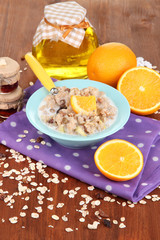 Useful oatmeal in bowl with fruit on wooden table close-up