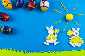 Obraz na płótnie Canvas Easter bunnies and colored eggs on blue background