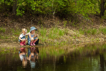 Little girls are fishing on lake in forest